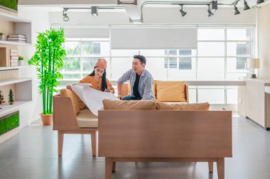 İki profesyonel, parlak ve modern bir çalışma alanında büyük bir planlama tablosunu gözden geçiriyorlar. Sahne, bir başlangıç ortamında takım çalışması, stratejik düşünme ve işbirlikçi proje gelişimini yansıtıyor