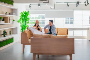 İki profesyonel, parlak ve modern bir çalışma alanında büyük bir planlama tablosunu gözden geçiriyorlar. Sahne, bir başlangıç ortamında takım çalışması, stratejik düşünme ve işbirlikçi proje gelişimini yansıtıyor