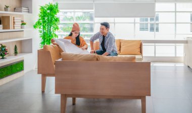 İki profesyonel, parlak ve modern bir çalışma alanında büyük bir planlama tablosunu gözden geçiriyorlar. Sahne, bir başlangıç ortamında takım çalışması, stratejik düşünme ve işbirlikçi proje gelişimini yansıtıyor