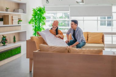 İki profesyonel, parlak ve modern bir çalışma alanında büyük bir planlama tablosunu gözden geçiriyorlar. Sahne, bir başlangıç ortamında takım çalışması, stratejik düşünme ve işbirlikçi proje gelişimini yansıtıyor