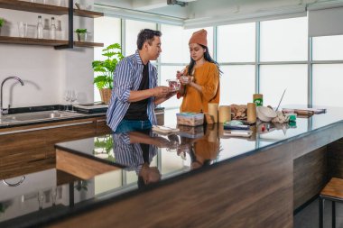 İki girişimci, modern bir çalışma alanında sürdürülebilir ambalaj örneklerini gözden geçiriyorlar. Çevre dostu materyaller ve ürün prototipleriyle çevrelenmiş olarak ürün geliştirme ve markalaşma fikirlerini tartışıyorlar.