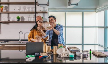 İki girişimci, modern bir çalışma alanında sürdürülebilir ambalaj örneklerini gözden geçiriyorlar. Çevre dostu materyaller ve ürün prototipleriyle çevrelenmiş olarak ürün geliştirme ve markalaşma fikirlerini tartışıyorlar.