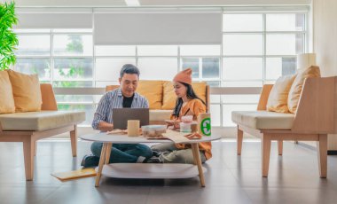 İki girişimci, modern bir çalışma alanında sürdürülebilir ambalaj örneklerini gözden geçiriyorlar. Çevre dostu materyaller ve ürün prototipleriyle çevrelenmiş olarak ürün geliştirme ve markalaşma fikirlerini tartışıyorlar.