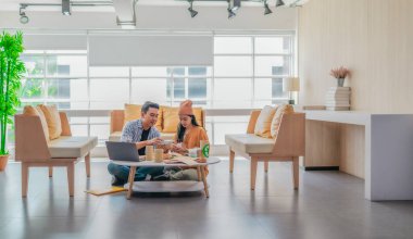 İki girişimci, modern bir çalışma alanında sürdürülebilir ambalaj örneklerini gözden geçiriyorlar. Çevre dostu materyaller ve ürün prototipleriyle çevrelenmiş olarak ürün geliştirme ve markalaşma fikirlerini tartışıyorlar.