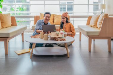 İki girişimci, modern bir çalışma alanında sürdürülebilir ambalaj örneklerini gözden geçiriyorlar. Çevre dostu materyaller ve ürün prototipleriyle çevrelenmiş olarak ürün geliştirme ve markalaşma fikirlerini tartışıyorlar.