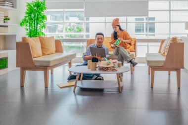 İki girişimci, modern bir çalışma alanında sürdürülebilir ambalaj örneklerini gözden geçiriyorlar. Çevre dostu materyaller ve ürün prototipleriyle çevrelenmiş olarak ürün geliştirme ve markalaşma fikirlerini tartışıyorlar.