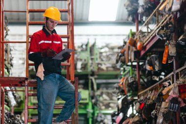 Erkek teknisyen elle kontrol ediyor depodaki otomobil parçalarını sayıyor organize araba parçalarıyla dolu. Endüstriyel hassasiyet, yüksek hacimli otomotiv ortamında el işi.