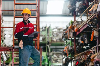 Erkek teknisyen elle kontrol ediyor depodaki otomobil parçalarını sayıyor organize araba parçalarıyla dolu. Endüstriyel hassasiyet, yüksek hacimli otomotiv ortamında el işi.