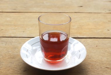 Tahta bir masada şeffaf cam bardakta servis edilen sıcak çay.