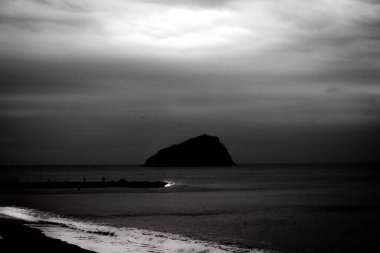 Karanlık deniz dalgaları Ligurian sahilinin kumlu sahillerine çarpar.