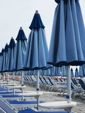 2024 yılında bir yaz günü, Ligurian hamamında bir plajda şemsiye ve iskemleler.