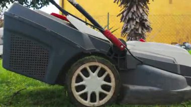 Çim biçme makinesi baharda yeşil bir çimenliğin çimlerini kesiyor bahçe işlerinin başlangıcıyla birlikte.