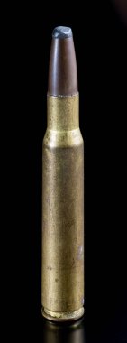 Siyah yüzeyde duran antika bir tüfek fişeğinin yakın çekimi.