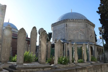 Güneşli bir günde cami kubbesinin önüne eski mezar taşları konur. 