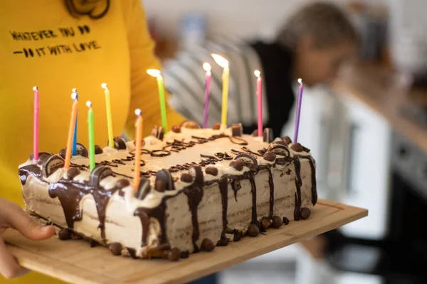 lady wearing a yellow shirt taking birthday cake with candles on it