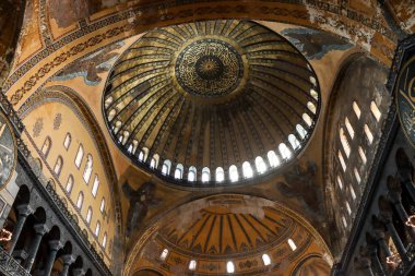 roof of Hagia Sophia with light peeking through windows and ancient paintings on the walls from below