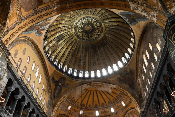 roof of Hagia Sophia with light peeking through windows and ancient paintings on the walls from below