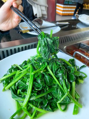 HotPot restoranında Çin usulü ıspanak yemek çubuklarıyla kaldırıldı.