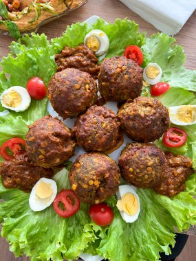 Marul, domates ve yumurtalarla süslü bir tabağa yerleştirilmiş mercimekli geleneksel köfte tabağı.