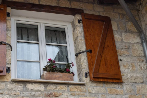 Uzak bir köyde taş bir evin ahşap kapıları olan şirin bir pencere.