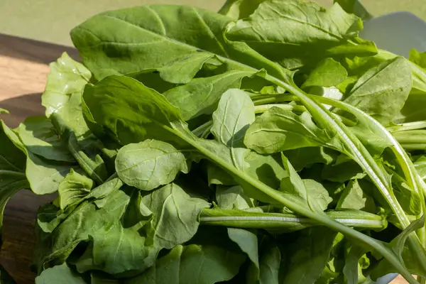 Tahta masanın üzerinde güneş ışığında bir demet roket yaprağı