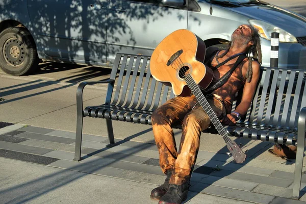 stock image young woman sitting on bench and playing guitar