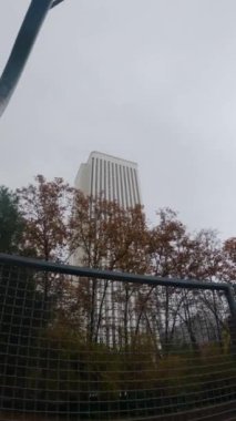 Basketbol sahasında geniş açı yavaş çekim ters pota. Sonbahar ağaçları ve Madrid 'de beyaz kule var.