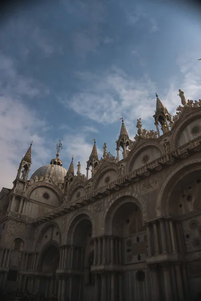 Basilica di San Marco 'nun ihtişamı dikey geniş açılı bir açıyla çekildi, kabarık beyaz bulutlu, dingin mavi bir gökyüzü tarafından tamamlandı..