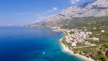 Kristal berraklığında, Adriyatik Denizi 'nin turkuaz koyunda Hırvatistan' ın Istria kentindeki Cape Kamenjak 'ın arka planında yeşil çamlar ve kayalar bulunuyor..