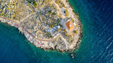Makarska, Hırvatistan. Adriyatik Denizi kıyısındaki eski deniz feneri gün batımında sokak lambalı kaldırım taşlarının geçtiği cadde boyunca. Bulutlu akşam gökyüzü. Yaz manzarası.