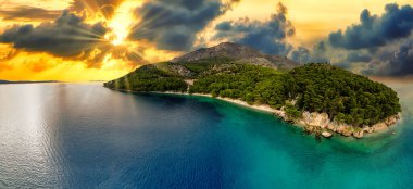 İnanılmaz günbatımı deniz manzarası, doğanın güzelliği. Manzaralı deniz manzarası, kayalık sahil ve kumlu sahil, altın renkli gökyüzü ve güneş, dış seyahat arka planı, Hırvatistan