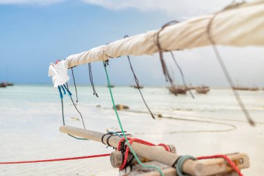 inside view of a dhow's sails and deck with bellowing sails against a blue sky