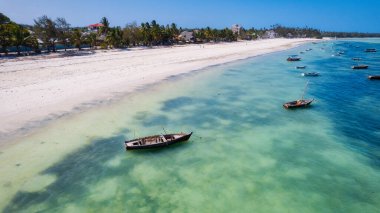 This aerial photo of Kiwengwa Beach in Zanzibar showcases the stunning natural beauty of the island, with its golden sand, turquoise waters, and lush foliage creating the perfect backdrop for a relaxing vacation.