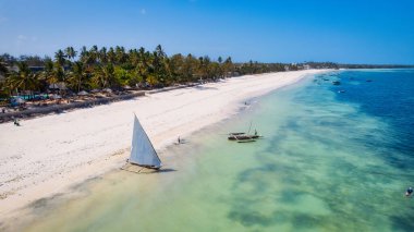 This aerial photo of Kiwengwa Beach in Zanzibar showcases the stunning natural beauty of the island, with its golden sand, turquoise waters, and lush foliage creating the perfect backdrop for a relaxing vacation.