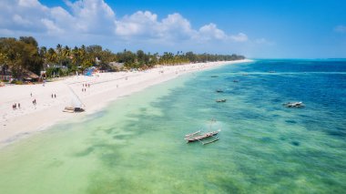 This aerial photo of Kiwengwa Beach in Zanzibar showcases the stunning natural beauty of the island, with its golden sand, turquoise waters, and lush foliage creating the perfect backdrop for a relaxing vacation.