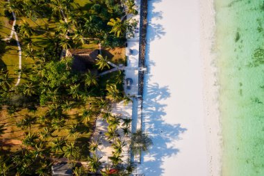 The aerial view of Zanzibar's Indian Ocean coastline is simply stunning, featuring palm trees, white sand, and sparkling blue waters. With luxurious hotels and a tropical landscape, it is the perfect destination for a summer holiday. 