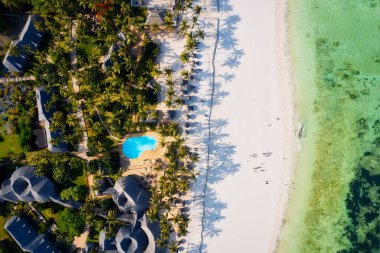 The aerial view of Zanzibar's Indian Ocean coastline is simply stunning, featuring palm trees, white sand, and sparkling blue waters. With luxurious hotels and a tropical landscape, it is the perfect destination for a summer holiday. 