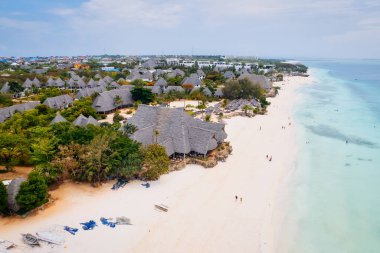 From above, the stunning beauty of Zanzibar's Nungwi Beach is captured in an aerial view with a yacht and palm trees on the sandy beach.