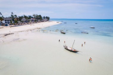 From above, the stunning beauty of Zanzibar's Nungwi Beach is captured in an aerial view with a yacht and palm trees on the sandy beach.