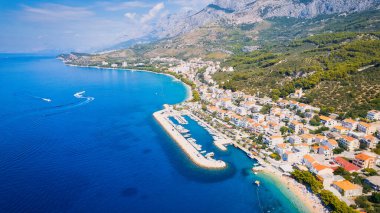 Croatia's harbor is a sight to behold from above. This breathtaking aerial view captures the colorful landscape filled with sailboats, motorboats, and luxurious yachts resting in a clear blue bay. Add this travel image to your collection of 