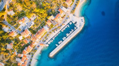 Croatia's harbor is a sight to behold from above. This breathtaking aerial view captures the colorful landscape filled with sailboats, motorboats, and luxurious yachts resting in a clear blue bay. Add this travel image to your collection of 