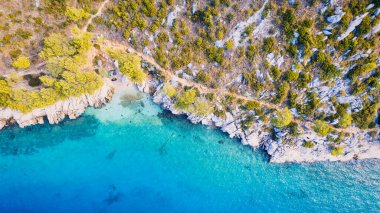 A drone captured the stunning aerial view of Croatia's coastal area, which features crystal-clear blue water and lush forests on land.