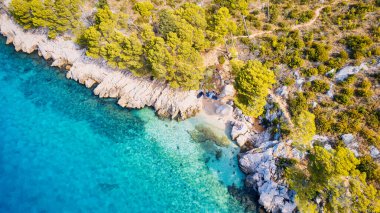 A drone captured the stunning aerial view of Croatia's coastal area, which features crystal-clear blue water and lush forests on land.
