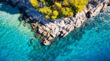 A drone captured the stunning aerial view of Croatia's coastal area, which features crystal-clear blue water and lush forests on land.