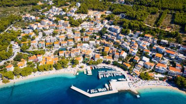 Croatia's harbor is a sight to behold from above. This breathtaking aerial view captures the colorful landscape filled with sailboats, motorboats, and luxurious yachts resting in a clear blue bay. Add this travel image to your collection of 