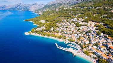 Croatia's harbor is a sight to behold from above. This breathtaking aerial view captures the colorful landscape filled with sailboats, motorboats, and luxurious yachts resting in a clear blue bay. Add this travel image to your collection of 