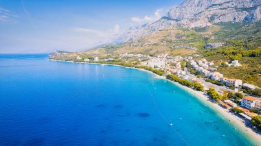 Hırvatistan 'ın büyüleyici kıyı kenti Makarska' ya yeni bir perspektiften bakın. Güneşli bir günde bu muhteşem insansız hava aracı çekim panoramasıyla..