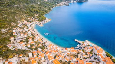 Take in the beauty of Croatia's coastal region from a new perspective with this stunning drone view, which features clear blue water and forested land.