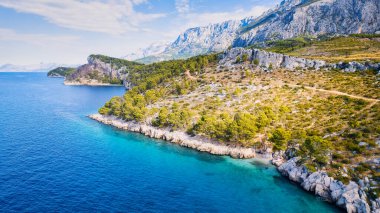 Take in the breathtaking aerial view of Makarska Riviera in Croatia, revealing a picturesque rocky beach and the vibrant turquoise water.