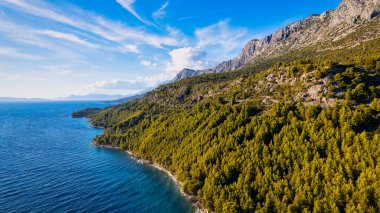 Take in the breathtaking aerial view of Makarska Riviera in Croatia, revealing a picturesque rocky beach and the vibrant turquoise water.